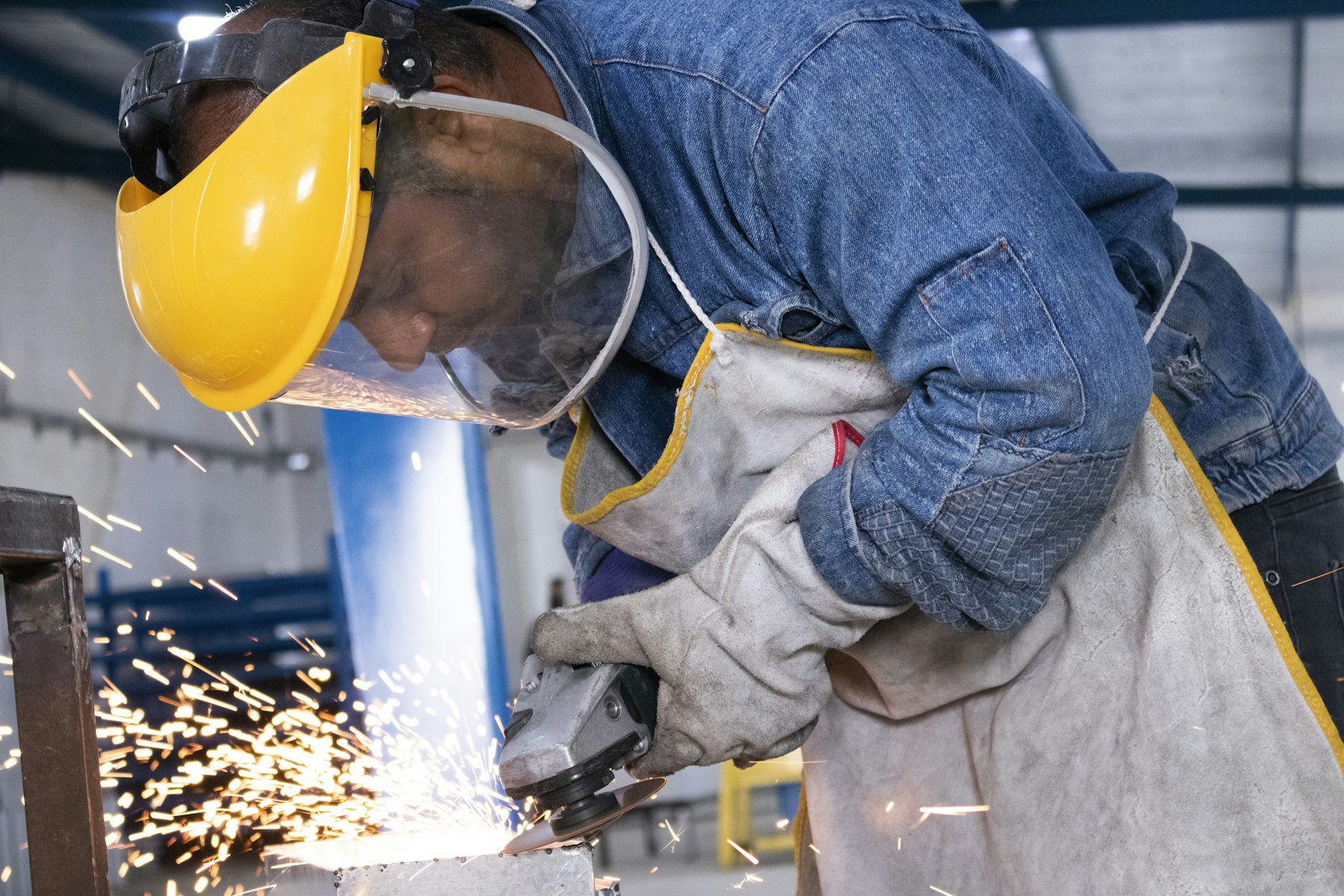 Técnico com capacete e viseira a trabalhar com rebarbadora